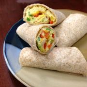 whole wheat burritos filled with egg and red and green pepper cut on a plate