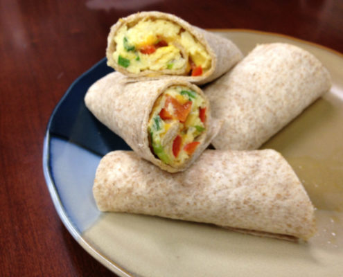 whole wheat burritos filled with egg and red and green pepper cut on a plate